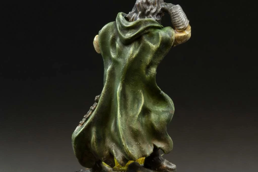 The classical highlighting effect showed on the printable 3d miniature. Fantasy character standing backwards with highlightings on his green cloak.